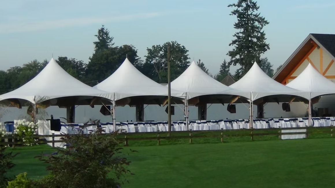 Row of marquee tents on a lawn set for a banquet
